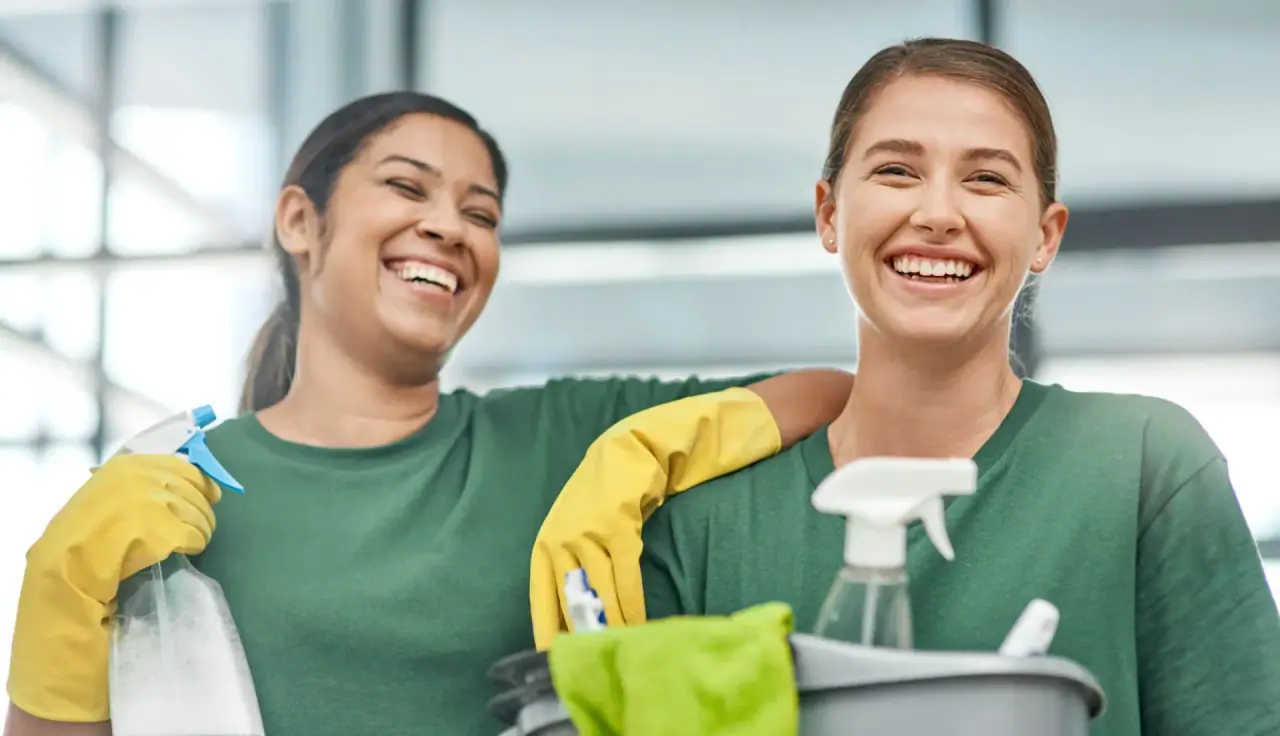 Two smiling uniformed cleaners with professional cleaning equipment